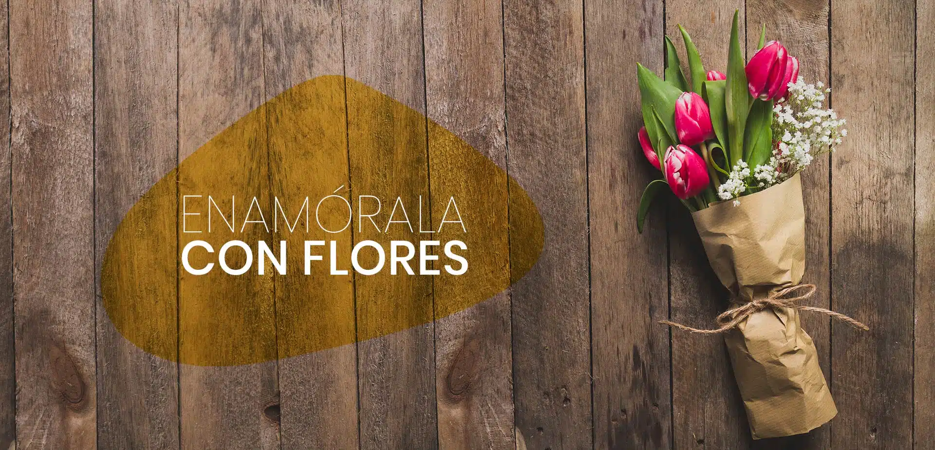 Wrapped bouquet of pink tulips and white baby’s breath on rustic wooden boards with Spanish text enamórala con flores