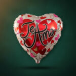 Globo metálico en forma de corazón con la frase Te Amo y estampado de corazones de colores sobre fondo verde oscuro