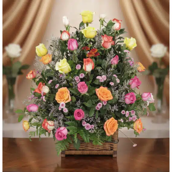 Arreglo DONNIA: Cesta Elegante con 34 Rosas para Sorprender Arreglo floral DONNIA en cesta de mimbre con 34 rosas de colores variados (rosas, amarillas, naranjas) y follaje verde, sobre