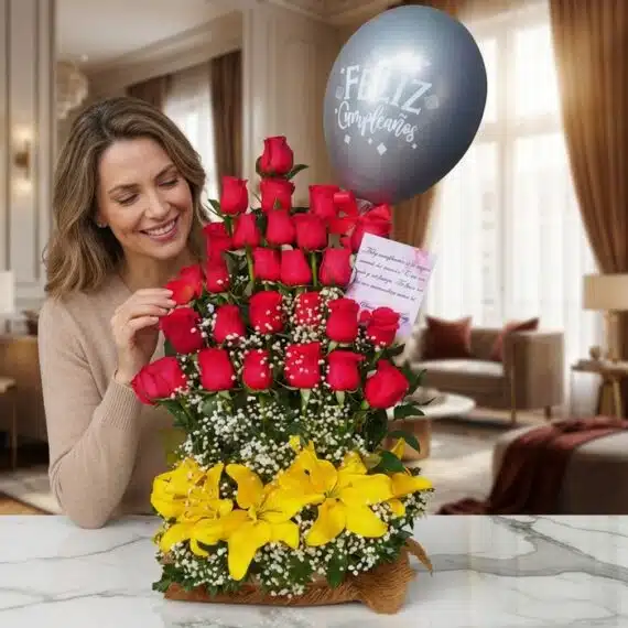 Mujer sonriente admirando un Arreglo Floral Exótico Gamma con rosas rojas, lirios amarillos y un globo de "Feliz Cumpleaños"