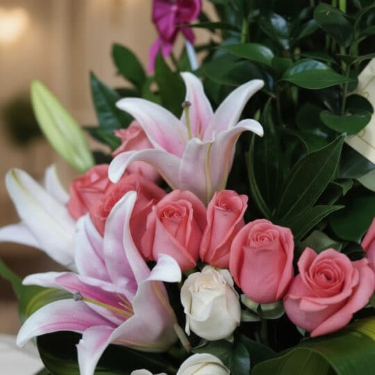 Primer plano extremo de un arreglo floral exótico primaveral con lirios blancos y rosas rosadas, mostrando texturas hiperreal