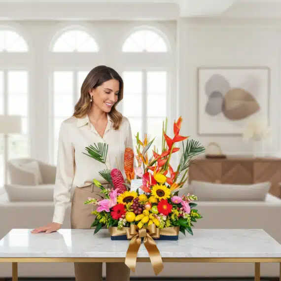 Mujer elegante admirando un Arreglo Floral con Frutas Hawai, destacando flores tropicales, girasoles y frutas exóticas en un