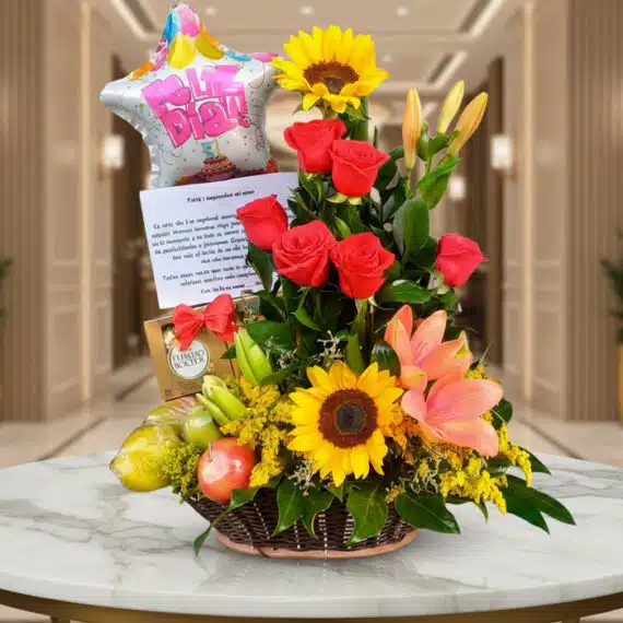 Arreglo Floral con Frutas Kiwano: Regalo Elegante y Fresco Arreglo floral premium con rosas rojas, girasoles, lirios, frutas kiwano y globo 'Feliz Día' sobre mesa de mármol en lobby el