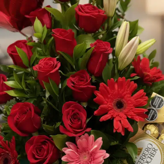 Primer plano extremo de un arreglo floral 'Te Amo' con rosas rojas vibrantes, lirios blancos y gerberas, mostrando texturas h