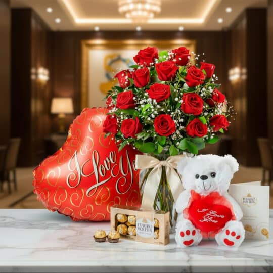 Jarrón Dulce Amor con rosas rojas, un oso de peluche blanco, chocolates Ferrero Rocher y un globo de 'I Love You' sobre mármo
