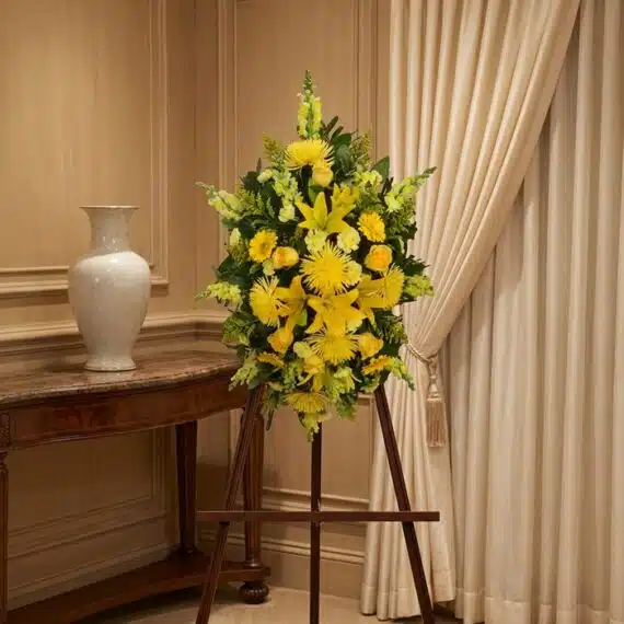 Pedestal de Homenaje «El Legado de Sebastian» con Flores Amarillas Pedestal de homenaje "El Legado de Sebastian" con un arreglo floral fúnebre de lirios y crisantemos amarillos, presentado ele