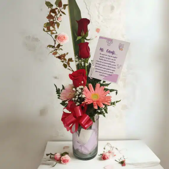 Solitario Pienso en Ti: Elegante Arreglo Floral con Rosas Rojas Arreglo floral Solitario Pienso en Ti con rosas rojas, gerberas y follaje en un jarrón de cristal, sobre un fondo elegante de