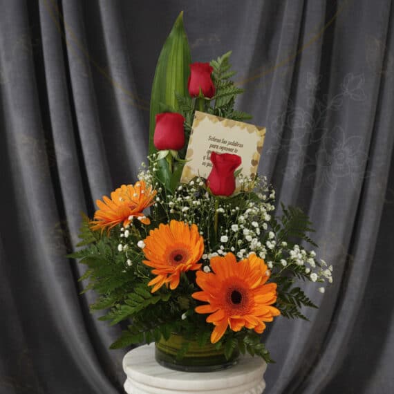 Solitario Tu Recuerdo: Elegante Arreglo Floral con Rosas y Gerberas Arreglo floral 'Solitario Tu Recuerdo' con tres rosas rojas, tres gerberas naranjas, follaje verde y flores blancas pequeñas,